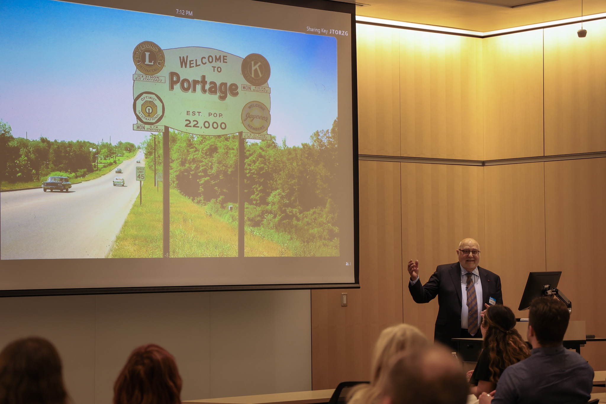 a speaker pointing to presentation at a large screen